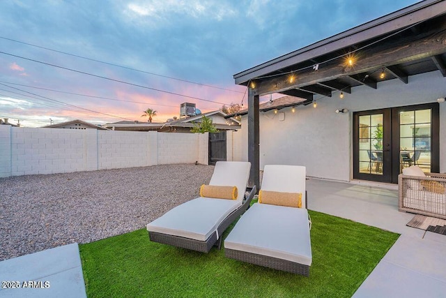 8547 E Roanoke Ave, Scottsdale, AZ 85257 - yard at dusk featuring a patio area, a fenced backyard, and french doors
