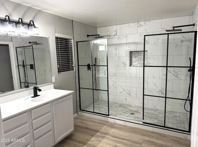 bathroom with vanity, wood-type flooring, a textured ceiling, and walk in shower