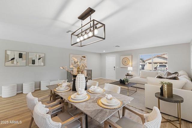 dining area with a notable chandelier and light hardwood / wood-style floors