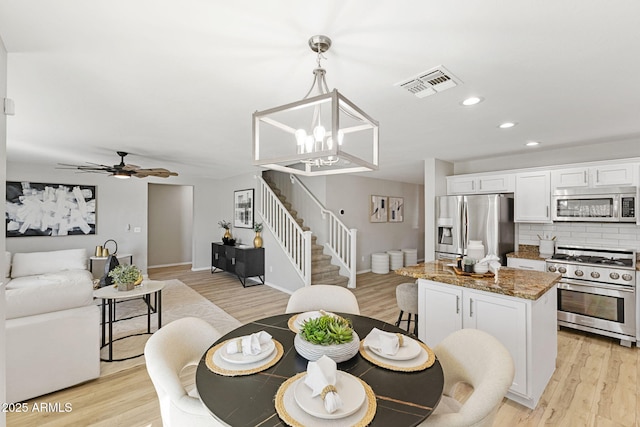 dining area featuring ceiling fan with notable chandelier and light hardwood / wood-style flooring