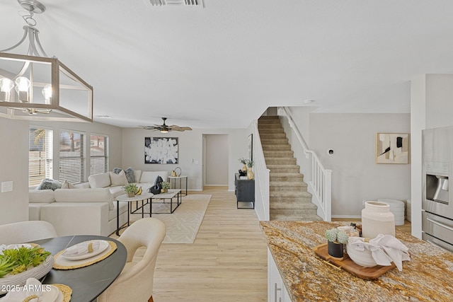 living room with washer / dryer, ceiling fan with notable chandelier, and light wood-type flooring