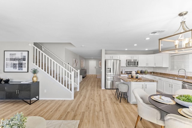 kitchen featuring sink, appliances with stainless steel finishes, hanging light fixtures, a kitchen breakfast bar, and white cabinets