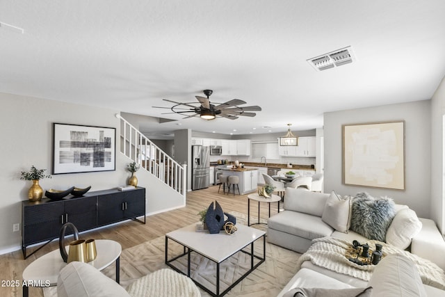 living room with ceiling fan, sink, and light wood-type flooring