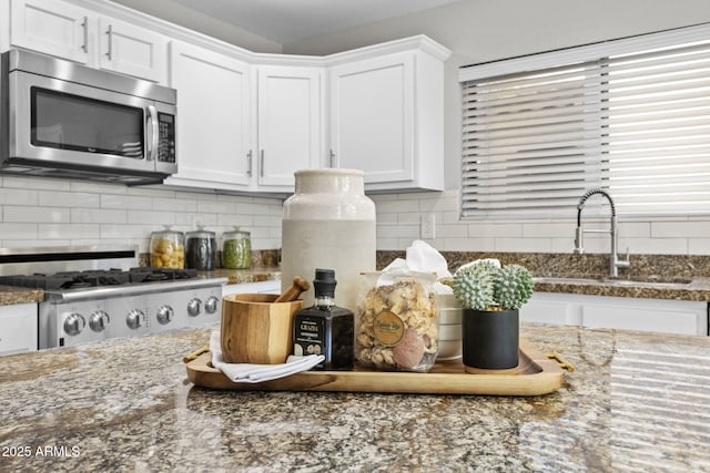 kitchen with white cabinetry, sink, tasteful backsplash, and stone counters