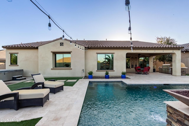 rear view of house with area for grilling, ceiling fan, a patio, and a pool with hot tub