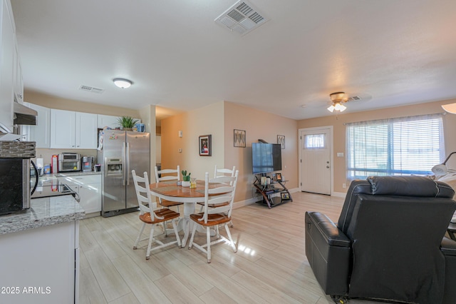 dining space with ceiling fan and light wood-type flooring