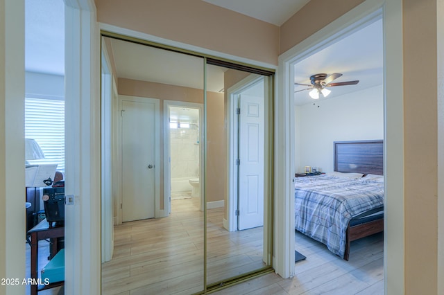 bedroom featuring ensuite bath, ceiling fan, a closet, and light wood-type flooring