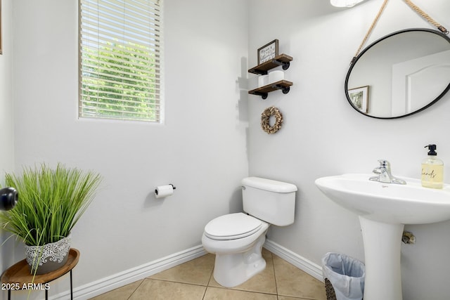 half bath with tile patterned floors, toilet, and baseboards