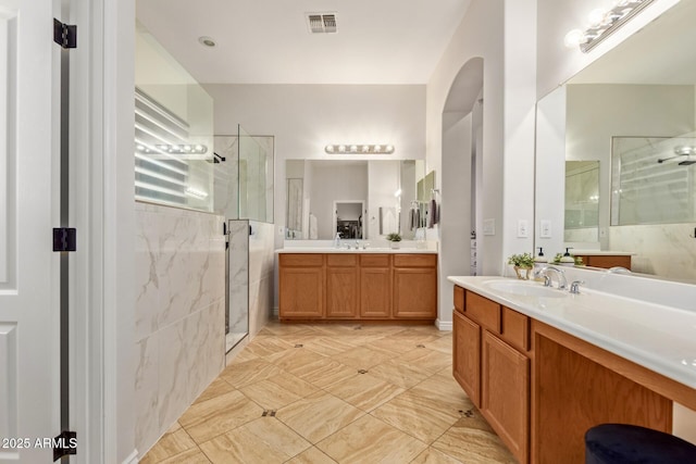 full bathroom with a shower stall and two vanities