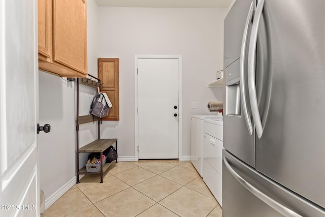 laundry area featuring cabinet space, washing machine and dryer, light tile patterned flooring, and baseboards