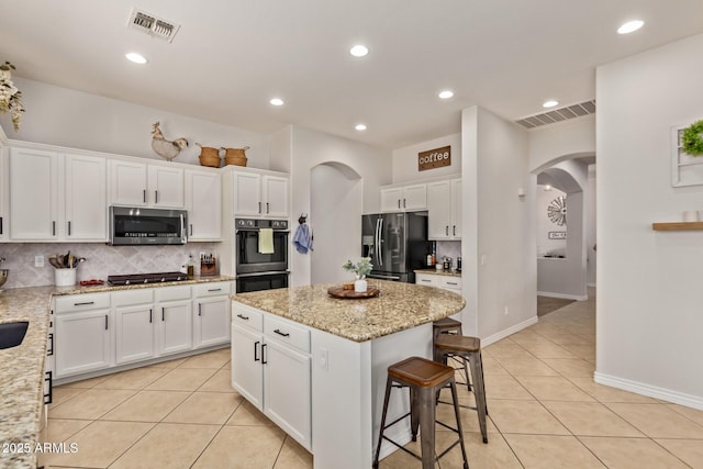kitchen featuring appliances with stainless steel finishes, arched walkways, light tile patterned flooring, backsplash, and recessed lighting