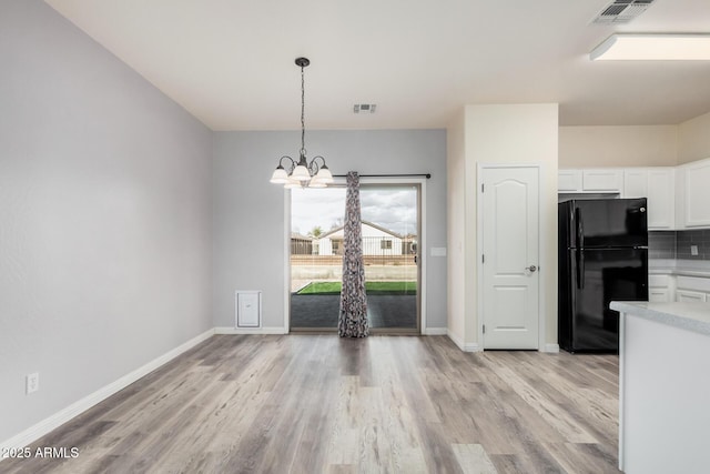 kitchen with light countertops, white cabinets, visible vents, and freestanding refrigerator