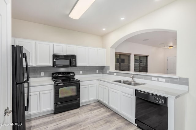 kitchen featuring backsplash, white cabinetry, black appliances, and a sink