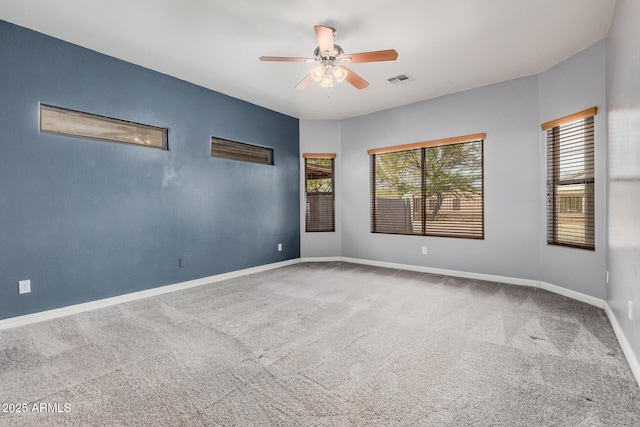 carpeted empty room with visible vents, ceiling fan, and baseboards