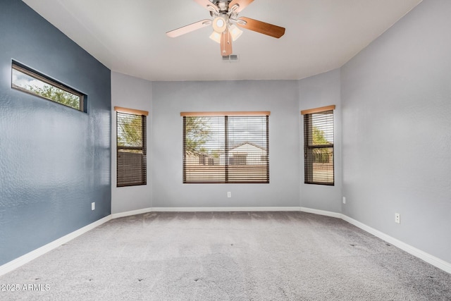 carpeted spare room with visible vents, a ceiling fan, and baseboards