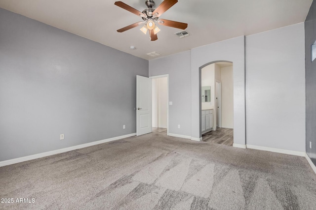 unfurnished bedroom with visible vents, baseboards, ensuite bath, arched walkways, and carpet flooring