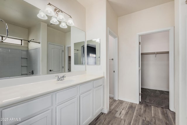 full bathroom featuring a walk in closet, baseboards, wood finished floors, and vanity