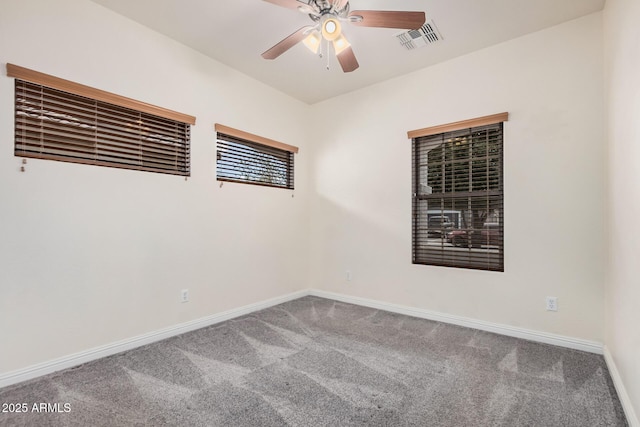 carpeted spare room featuring visible vents, baseboards, and ceiling fan