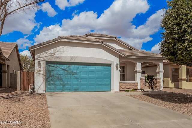 mediterranean / spanish house featuring a tiled roof, stucco siding, a garage, stone siding, and driveway