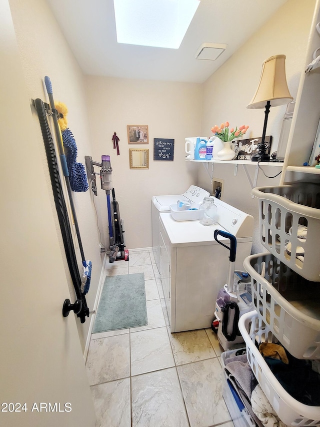 washroom featuring a skylight, light tile patterned flooring, and washer and dryer