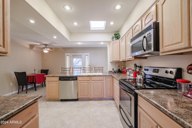 kitchen featuring a skylight, ceiling fan, light brown cabinets, sink, and appliances with stainless steel finishes