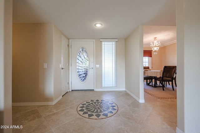 entryway with light tile patterned floors, ornamental molding, and a notable chandelier