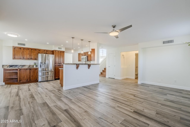 31259 N 42nd Pl, Cave Creek, AZ 85331 - kitchen with stainless steel appliances, brown cabinetry, light wood-style flooring, a kitchen breakfast bar, and a ceiling fan