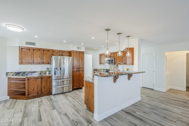 31259 N 42nd Pl, Cave Creek, AZ 85331 - kitchen with stainless steel appliances, brown cabinetry, a peninsula, stone countertops, and light wood-style floors