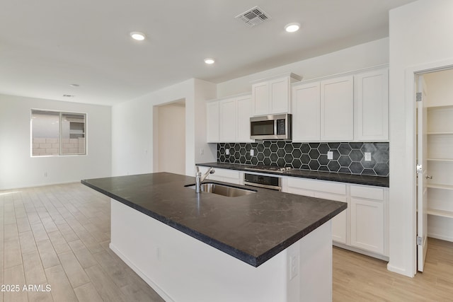 kitchen with a kitchen island with sink, white cabinetry, sink, and appliances with stainless steel finishes