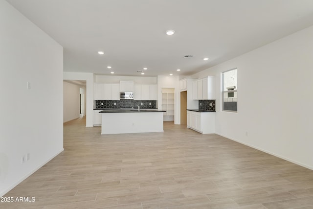 kitchen featuring sink, light hardwood / wood-style flooring, white cabinetry, and an island with sink