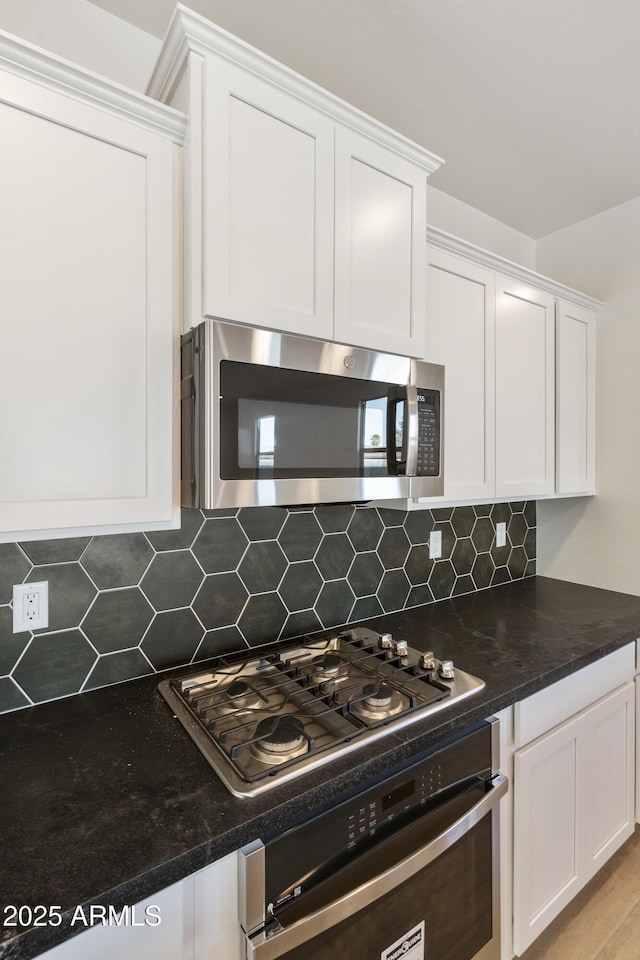 kitchen with appliances with stainless steel finishes, backsplash, light hardwood / wood-style floors, and white cabinetry