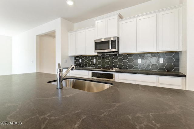 kitchen with appliances with stainless steel finishes, backsplash, white cabinetry, and sink