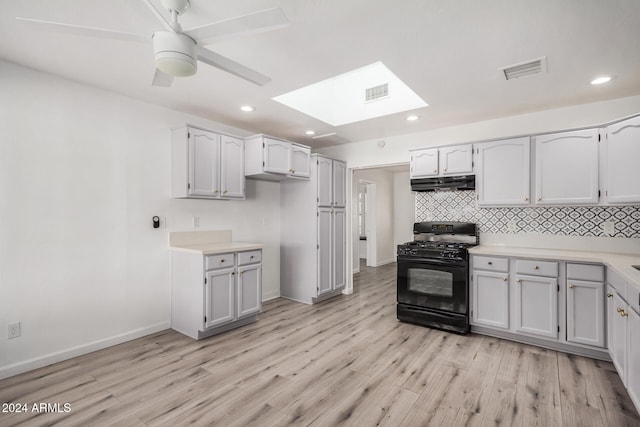 kitchen with gas stove, a skylight, white cabinetry, and light hardwood / wood-style flooring