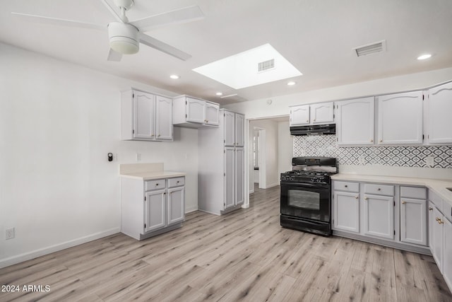 1818 E Monterey Way, Phoenix, AZ 85016 - kitchen featuring black gas stove, under cabinet range hood, a skylight, light wood-style flooring, and tasteful backsplash