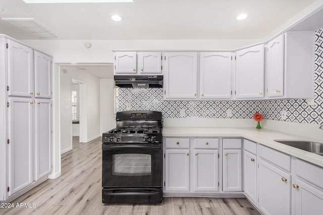 kitchen featuring backsplash, sink, light hardwood / wood-style flooring, white cabinets, and black gas stove