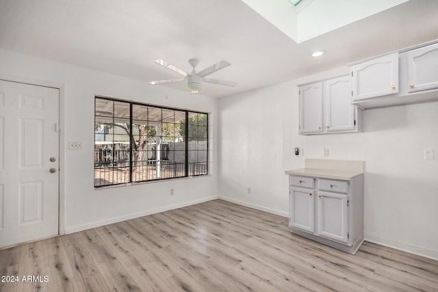 unfurnished dining area with ceiling fan, light hardwood / wood-style floors, and a skylight