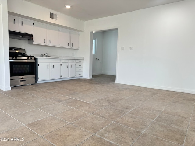 kitchen with stainless steel range with gas cooktop, sink, light tile floors, and white cabinetry