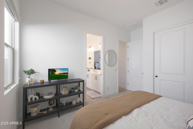 carpeted bedroom featuring ensuite bathroom and a closet