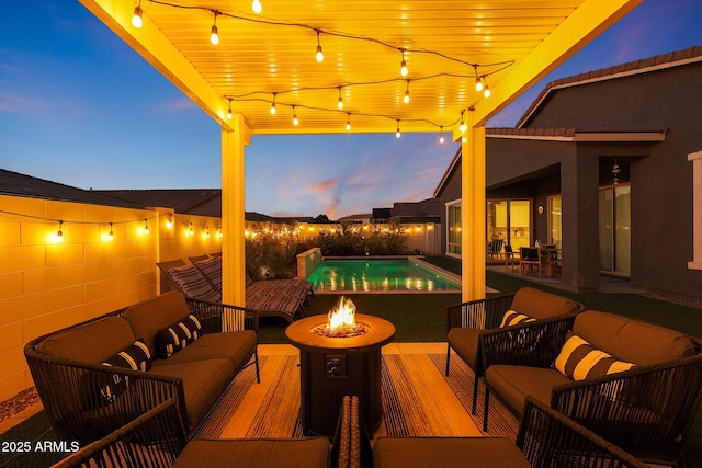 patio terrace at dusk featuring a fenced in pool and an outdoor living space with a fire pit