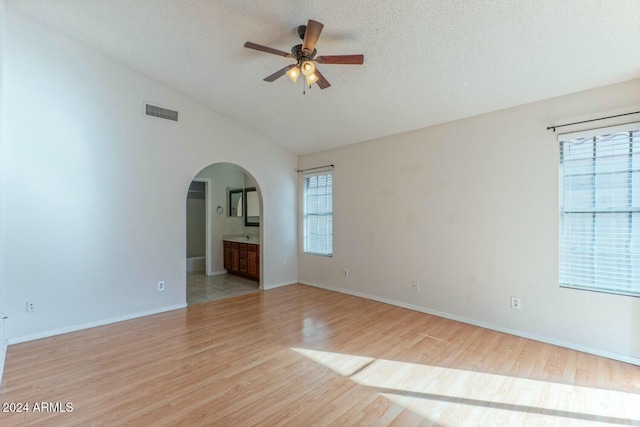 unfurnished room featuring light wood-type flooring, vaulted ceiling, and a wealth of natural light