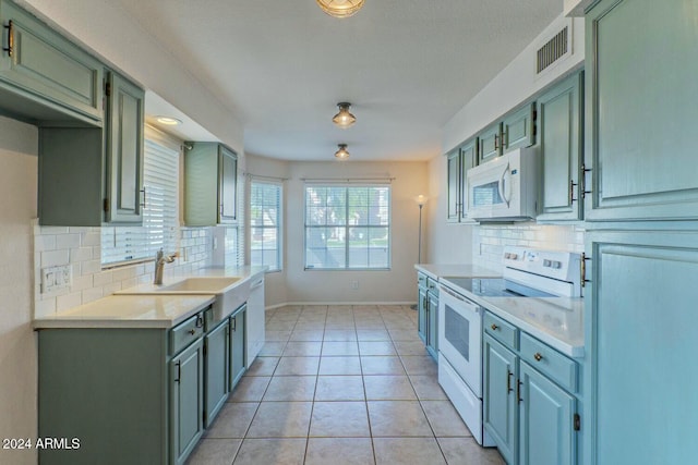 kitchen featuring decorative backsplash, white appliances, green cabinetry, and light tile patterned flooring