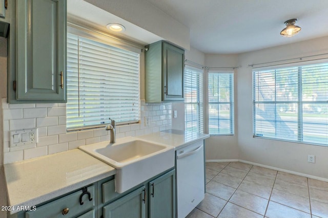 kitchen featuring dishwasher, green cabinets, sink, decorative backsplash, and light tile patterned floors