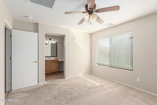 unfurnished bedroom featuring light colored carpet, baseboards, ensuite bathroom, and visible vents