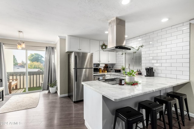 kitchen featuring kitchen peninsula, appliances with stainless steel finishes, dark hardwood / wood-style flooring, and island range hood