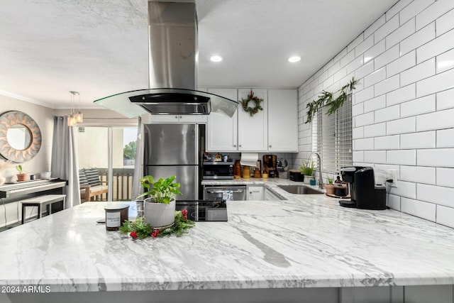 kitchen with light stone countertops, sink, island range hood, white cabinets, and appliances with stainless steel finishes