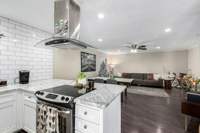 kitchen featuring light stone countertops, dark wood-type flooring, wall chimney range hood, electric stove, and white cabinets