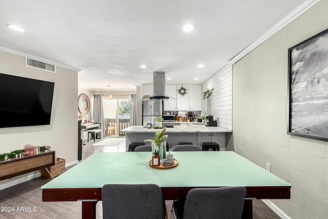 dining space with wood-type flooring and crown molding