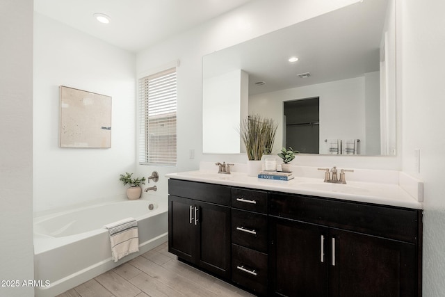 17652 W Fetlock Trl, Surprise, AZ 85387 - bathroom featuring double vanity, a garden tub, wood finished floors, and recessed lighting