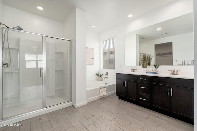 17652 W Fetlock Trl, Surprise, AZ 85387 - bathroom with a shower stall, a garden tub, double vanity, wood finished floors, and recessed lighting