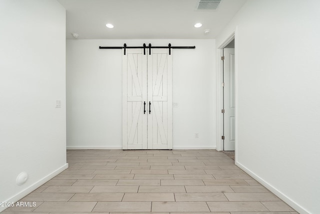 17652 W Fetlock Trl, Surprise, AZ 85387 - unfurnished bedroom with a barn door, recessed lighting, and wood finished floors